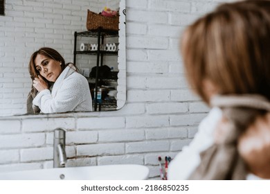 Hispanic Senior Middle Aged Woman Sitting On The Bathtub Corner Wiping Her Hair With Towel In Mexico Latin America