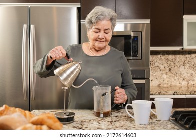 Hispanic Senior Woman Making Coffee In The Kitchen. 