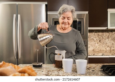 Hispanic Senior Woman Making Coffee In The Kitchen. 