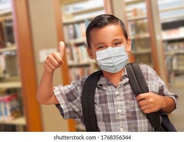 Hispanic Student Boy Wearing Face Mask with Thumbs Up and Backpack in the Library.