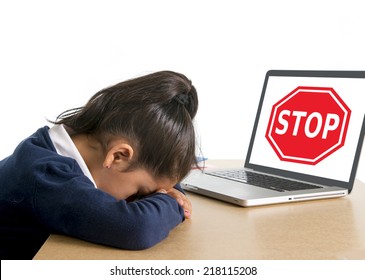 Hispanic Sweet Little Girl Crying And Suffering Internet Bullying And Abuse At School Sitting At Desk With Computer And Stop Sign 