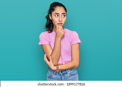 Hispanic Teenager Girl With Dental Braces Wearing Casual Clothes Thinking Worried About A Question, Concerned And Nervous With Hand On Chin 