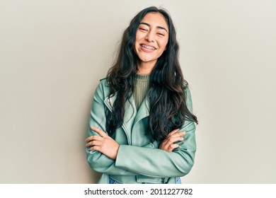 Hispanic Teenager Girl With Dental Braces Wearing Green Leather Jacket Happy Face Smiling With Crossed Arms Looking At The Camera. Positive Person. 