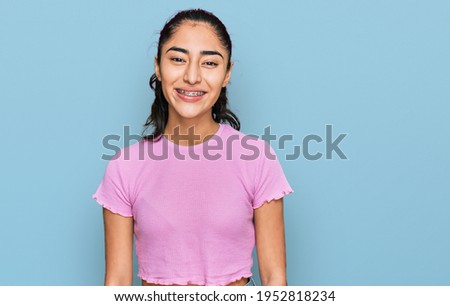 Hispanic teenager girl with dental braces wearing casual clothes with a happy and cool smile on face. lucky person. 