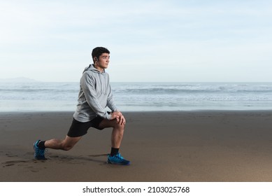 Hispanic teenager stretching at the beach while is focused on his goals - Powered by Shutterstock