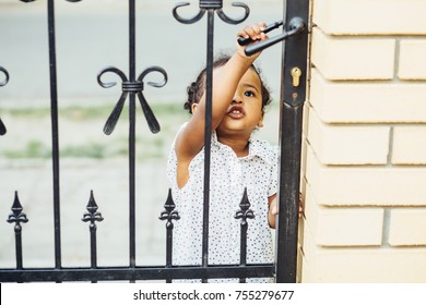 Hispanic Toddler Girl Two Years Old Opening Or Closing Gate. Baby Girl Opening The House Fence.