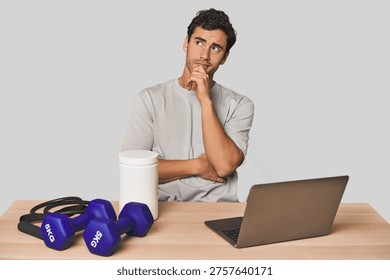 Hispanic trainer planning workout thinking and looking up, being reflective, contemplating, having a fantasy.