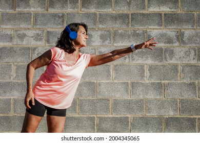 Hispanic Woman 60 Years Old With Sportswear And Headphones Stretching Arm