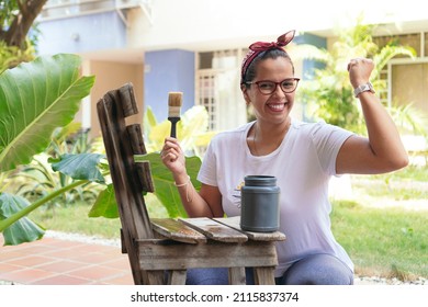 Hispanic Woman In The Backyard Paints An Old Chair And Smiling