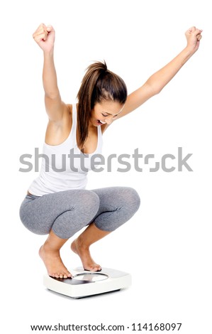 Hispanic woman celebrating and cheering a weightloss goal achievement isolated on white and on a scale