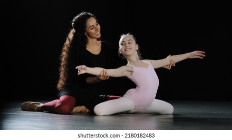 Hispanic woman coach dance trainer teacher with long curly hair help girl teenager bend back holding hands at side sitting on floor ballerina gymnast stretching advice trains position ballet class  - Powered by Shutterstock