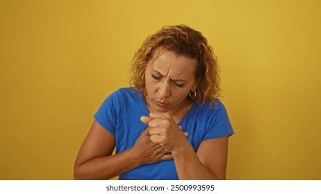 Hispanic woman coughing intensely while holding her chest against a yellow background, depicting illness or respiratory distress. - Powered by Shutterstock