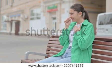 Hispanic Woman Coughing while Sitting on Bench Outdoor