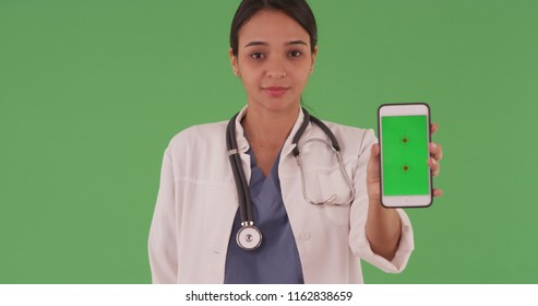 Hispanic Woman Doctor Holding Phone With Green Screen To Camera On Greenscreen