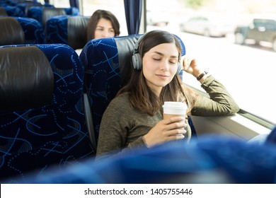 Hispanic Woman Enjoying Music And Coffee While Sitting In Bus