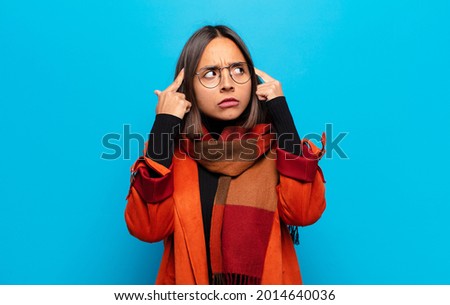 hispanic woman feeling confused or doubting, concentrating on an idea, thinking hard, looking to copy space on side