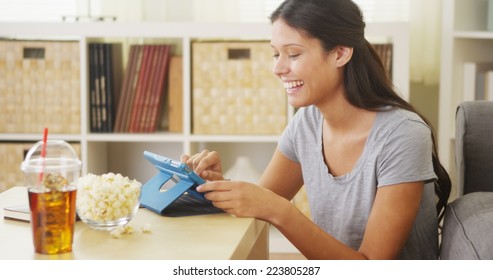 Hispanic Woman Laughing And Using Tablet On Coffee Table