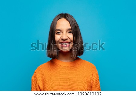 hispanic woman looking happy and goofy with a broad, fun, loony smile and eyes wide open