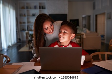 Hispanic Woman Looking Over Her SonÕs Shoulder While He Does His Homework Using Laptop Computer