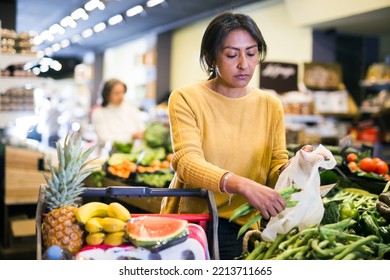 Hispanic Woman Making Purchases In Grocery Store, Putting Fresh Green Beans In Plastic Bag ..