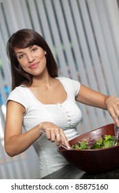 Hispanic woman mixing and tossing salad