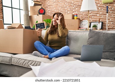 Hispanic Woman Moving To A New Home Smiling Happy Doing Ok Sign With Hand On Eye Looking Through Fingers 