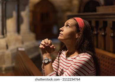 Hispanic woman praying with clasped hands in cathedral