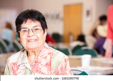 Hispanic Woman Smiling In A Busy Senior Center