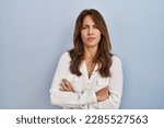 Hispanic woman standing over isolated background skeptic and nervous, disapproving expression on face with crossed arms. negative person. 