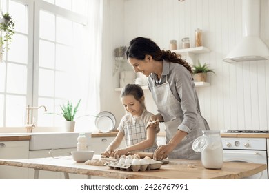 Hispanic woman teach little daughter to cook, prepare homemade dough for pastries, make holiday pie or cookies on weekend leisure in kitchen at home. Natural products, healthy eating, kid development - Powered by Shutterstock