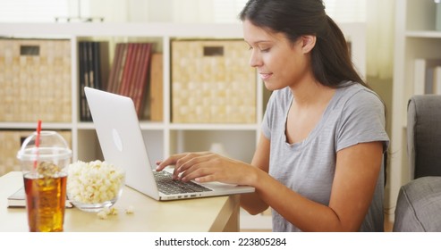 Hispanic Woman Using Laptop On Coffee Table