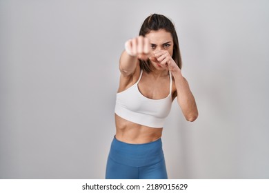 Hispanic woman wearing sportswear over isolated background punching fist to fight, aggressive and angry attack, threat and violence  - Powered by Shutterstock