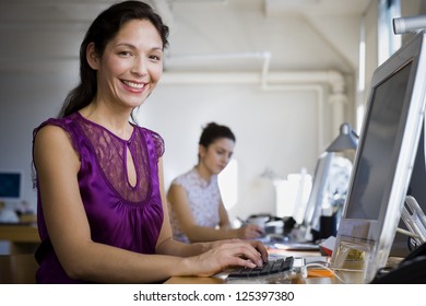 Hispanic Woman Working On Computer At Her Desk