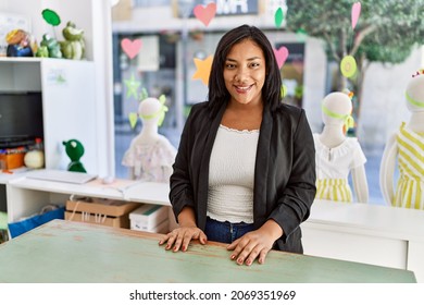 Hispanic Woman Working As Shop Assistant At Children Clothes Small Retail Trade. Sales Assistant Smiling Happy At Shopping Counter