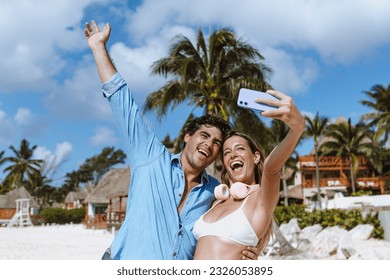 hispanic young couple taking photo selfie on beach vacations or holidays in Mexico Latin America, Caribbean and tropical destination  - Powered by Shutterstock