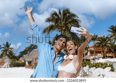 hispanic young couple taking photo selfie on beach vacations or holidays in Mexico Latin America, Caribbean and tropical destination 