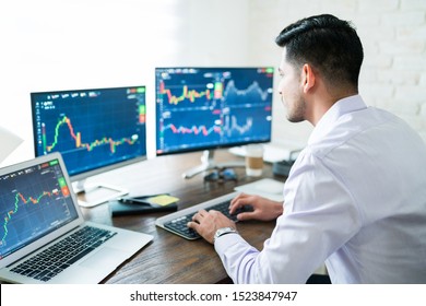 Hispanic young male stock trader typing on keyboard while using computer at home - Shutterstock ID 1523847947