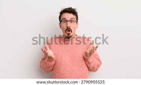 hispanic young man feeling extremely shocked and surprised, anxious and panicking, with a stressed and horrified look