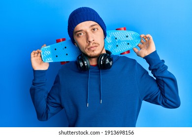 Hispanic young man holding skate relaxed with serious expression on face. simple and natural looking at the camera.  - Powered by Shutterstock