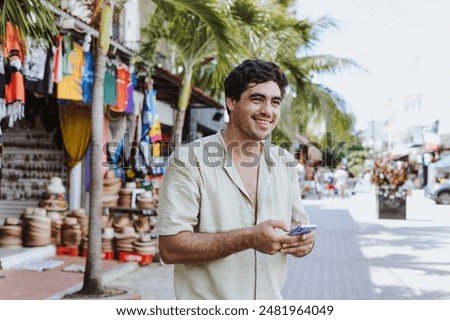hispanic young man using mobile phone on vacations or holidays in Mexico Latin America, Caribbean and tropical destination	