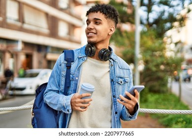 Hispanic young man using smartphone drinking a coffee at the street - Powered by Shutterstock