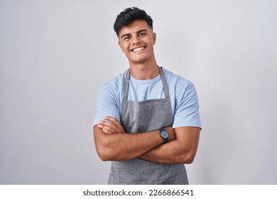 Hispanic young man wearing apron over white background happy face smiling with crossed arms looking at the camera. positive person.  - Powered by Shutterstock