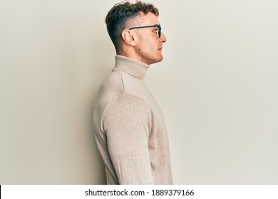 Hispanic Young Man Wearing Casual Turtleneck Sweater Looking To Side, Relax Profile Pose With Natural Face And Confident Smile. 