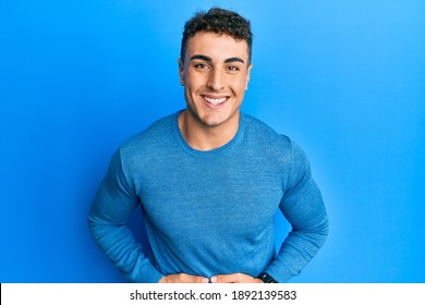 Hispanic young man wearing casual winter sweater smiling and laughing hard out loud because funny crazy joke with hands on body. 