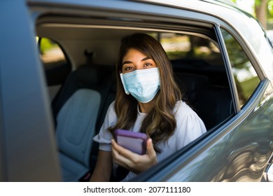 Hispanic Young Woman With A Face Mask Looking At The Camera While Taking A Ride Share Car During The Pandemic