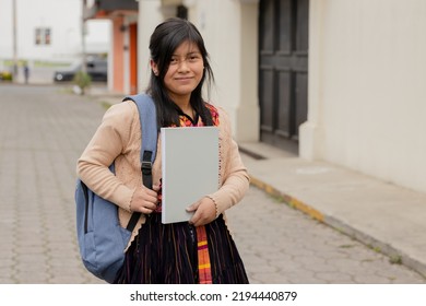 Hispanic young woman with notebook and backpack outside school in rural area - Mayan woman ready to go to study - Latina student in the city - Powered by Shutterstock