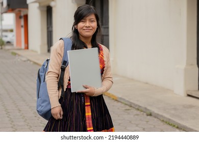 Hispanic Young Woman With Notebook And Backpack Outside School In The Village - Mayan Teenager Ready To Go To Study - Latina Student In The City