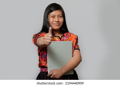 Hispanic Young Woman With Notebook And Thumb Up - Mayan Teenager Ready To Go To Study - Latina Student On White Background