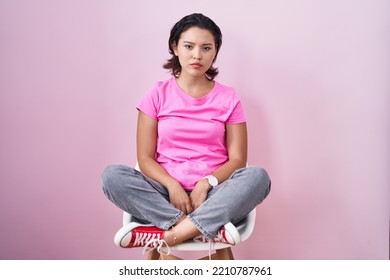 Hispanic Young Woman Sitting On Chair Over Pink Background Skeptic And Nervous, Frowning Upset Because Of Problem. Negative Person. 