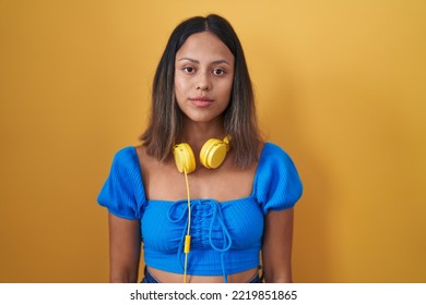 Hispanic Young Woman Standing Over Yellow Background Relaxed With Serious Expression On Face. Simple And Natural Looking At The Camera. 